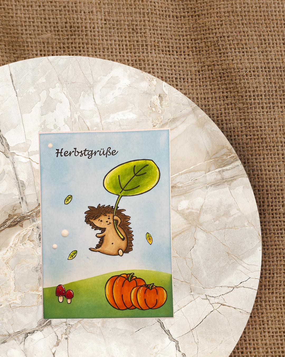 Karte mit fliegendem Igel und Blatt in der Hand, Text Herbstgrüße