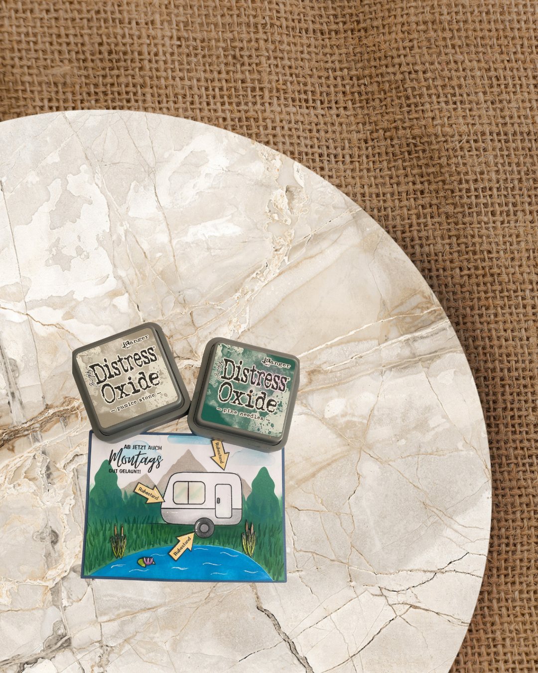 Karte mit einem Campingwagen an einem See mit Seerose und Seegras im Gras stehend. Im Hintergrund Berge und Bäume. 3 orange Pfeile mit Ruhestand drauf um den Campingwagen angeordnet. Spruch "Ab jetzt auch Montags immer gut gelaunt"