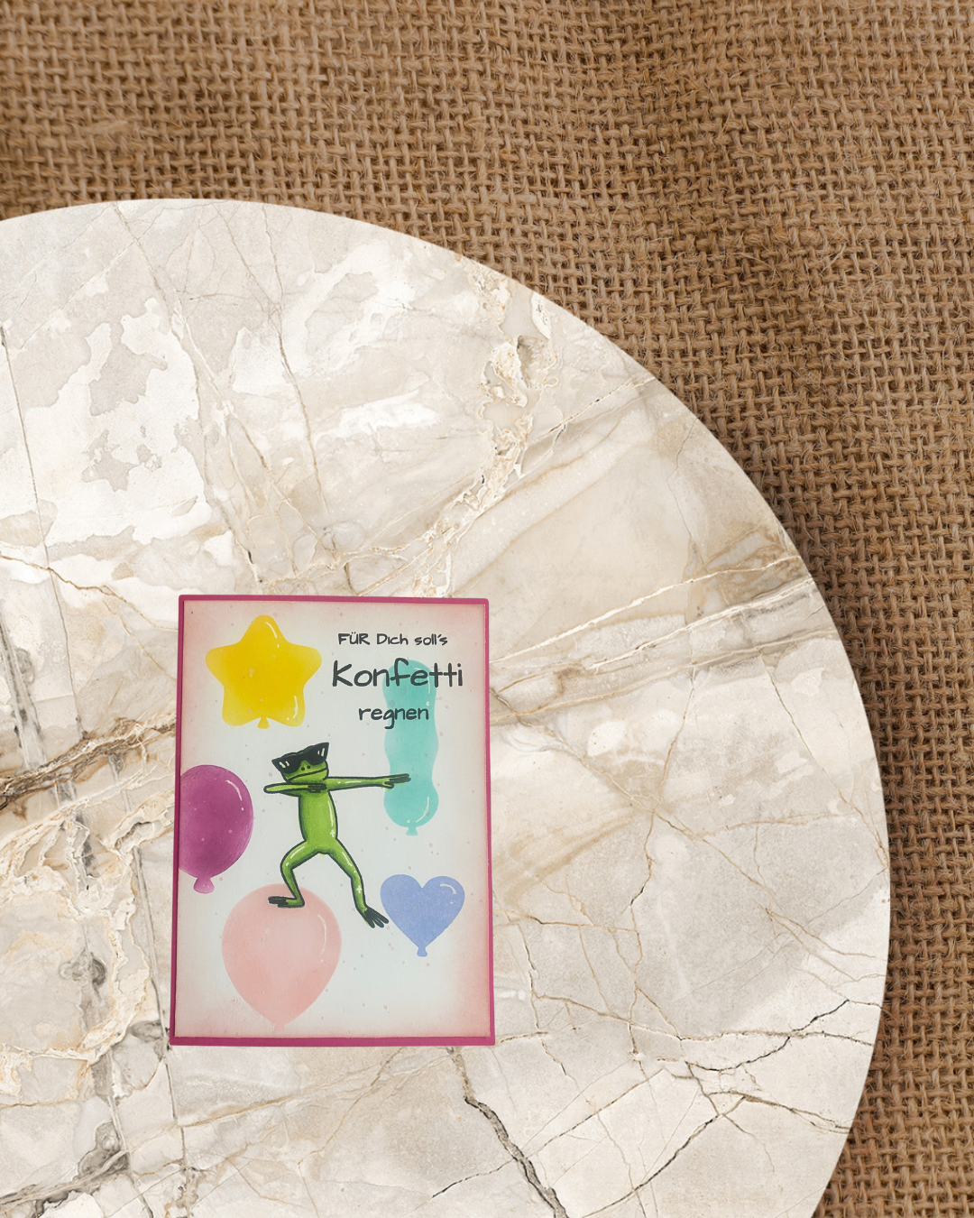Karte mit einem Collen Frosch mit Sonnenbrille. Im Hintergrund verschieden farbige Luftballons in unterschiedlichen Größen und formen. Spruch Für dich soll´s Konfetti regnen.