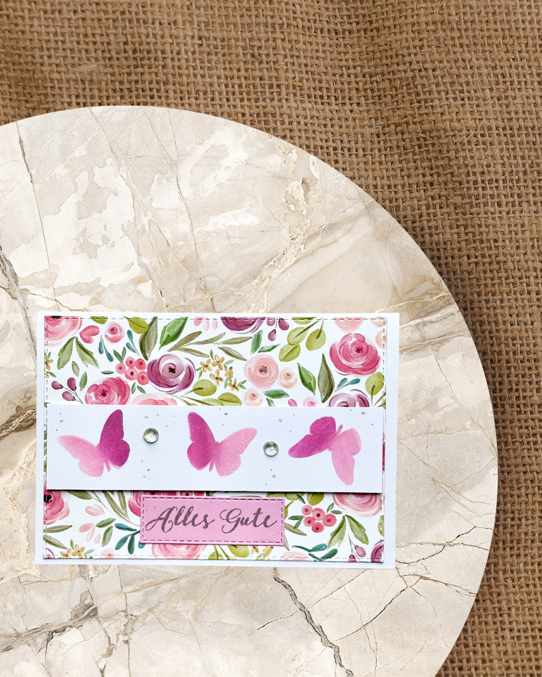 Karte mit Blumenmotiv und Schmetterlingbanner, Schriftzug Alles Gute