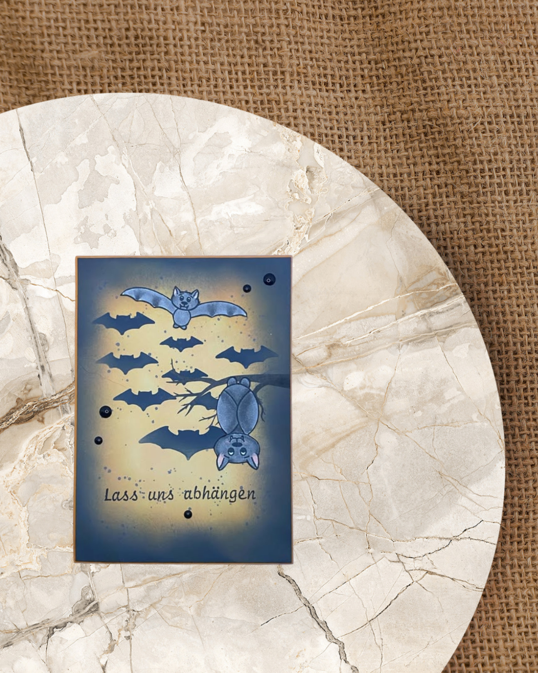 Schwarz/Orange Karten mit einer hängenden Fledermaus am Ast und einer fliegenden. Im Hintergrund Schatten vieler kleinerer Fledermäuse