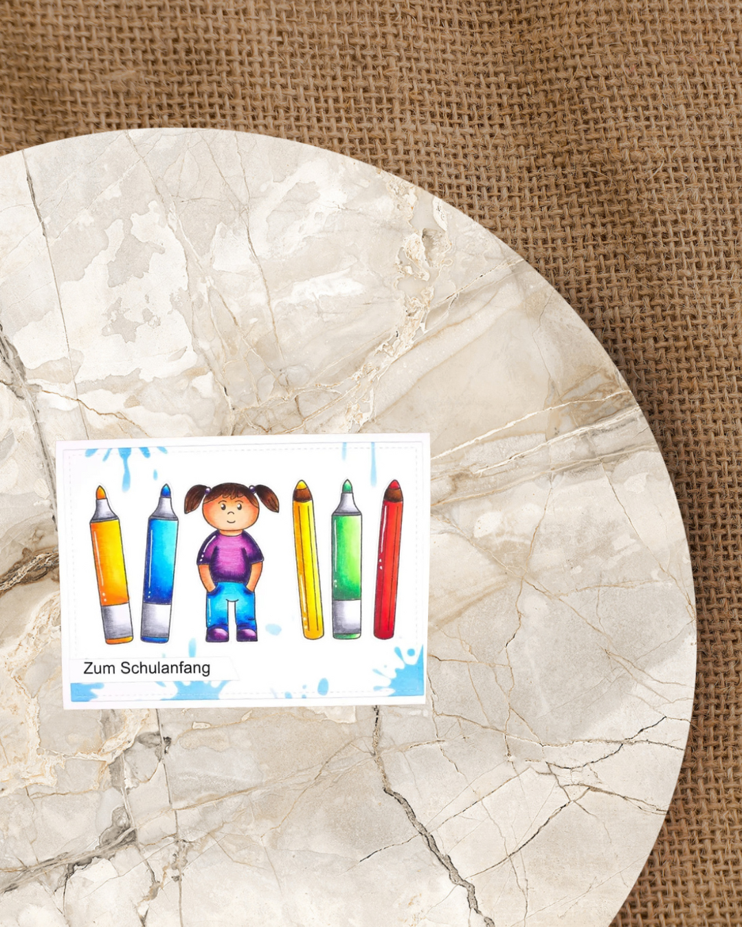 Ein Mädchen in der Mitte der Karte, rechts und links Buntstifte. Rechts unten der Spruch Zum Schulanfang