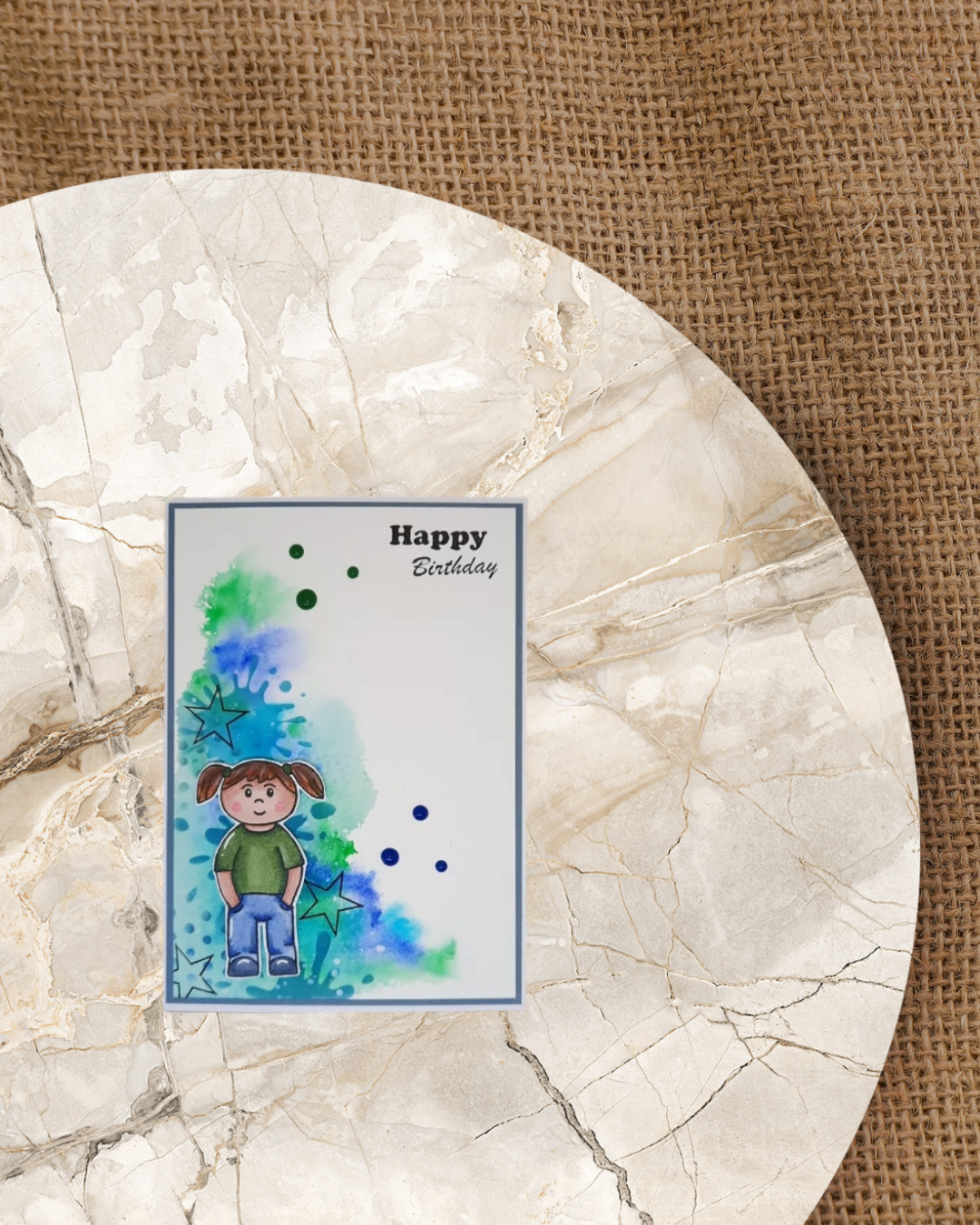 Karte mit einem stehenden Mädchen im Hintergrund in blau/grüne Kleckse. Spruch Happy Birthday