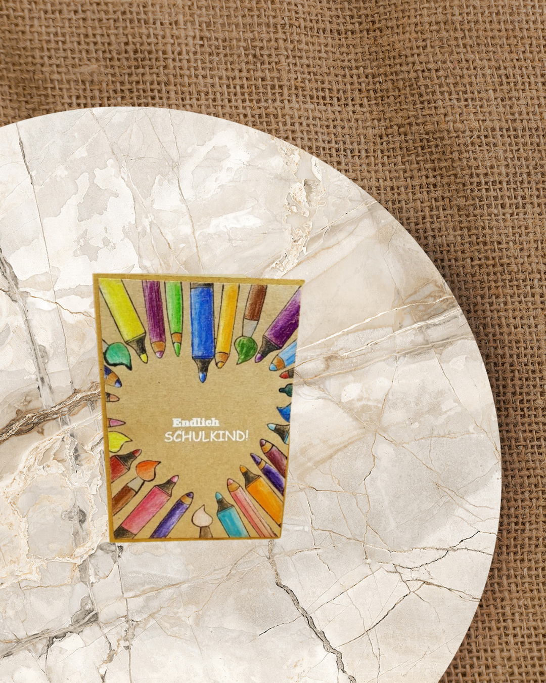 Karte in Kraftfarbe mit vielen Buntstiften die ein Herz in der Mitte bilden. In der Mitte der Spruch Endlich Schulkind