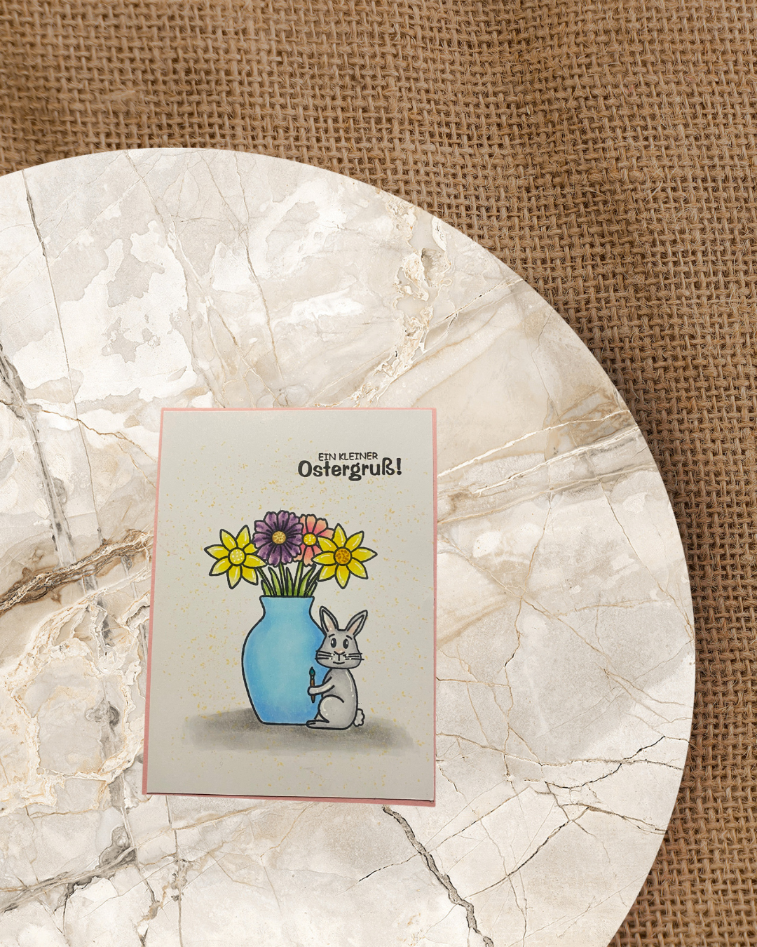 Karten zu Ostern mit einer Blumenvase und Strauß. Daneben sitzend ein Hase mit einem Pinsel in der Pfote