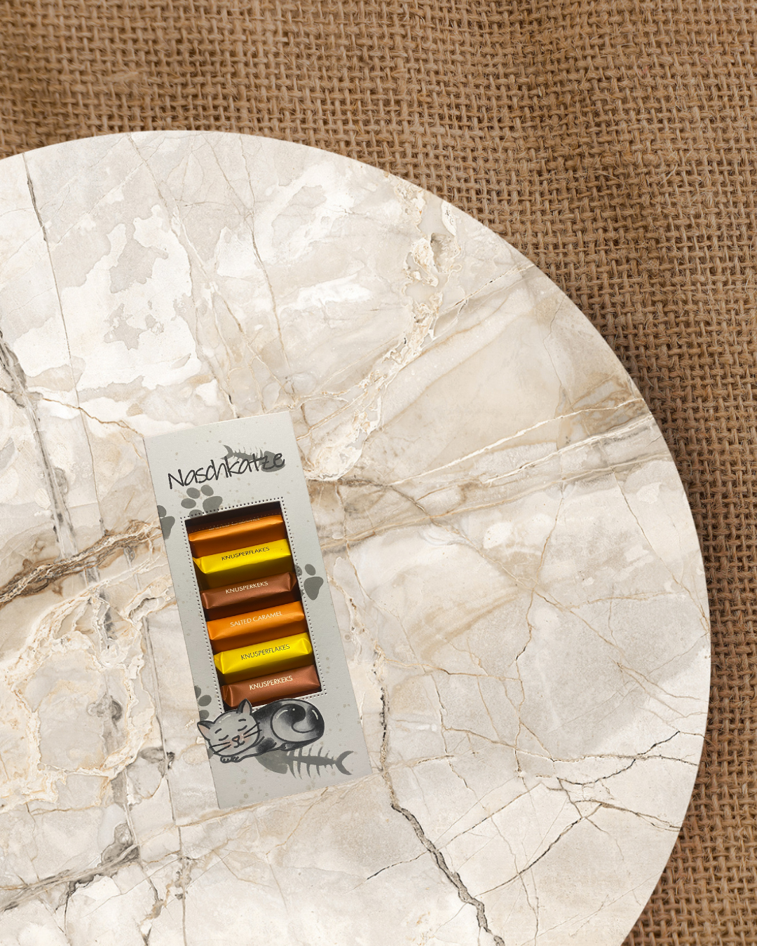 Schokoladentafelverpackung für kleine Tafeln mit Sichtfenster. Darauf eine Schlafende Katze mit dem Spruch Nachkatze. Im Hintergrund grau Tatzen und Fischgräten