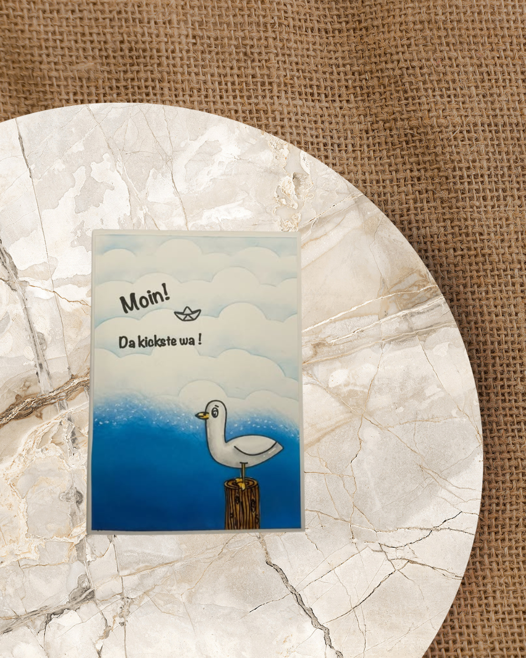 Eine Move die auf einem Baumstamm im Meer sitzt. Spruch ist Moin da kickste wa