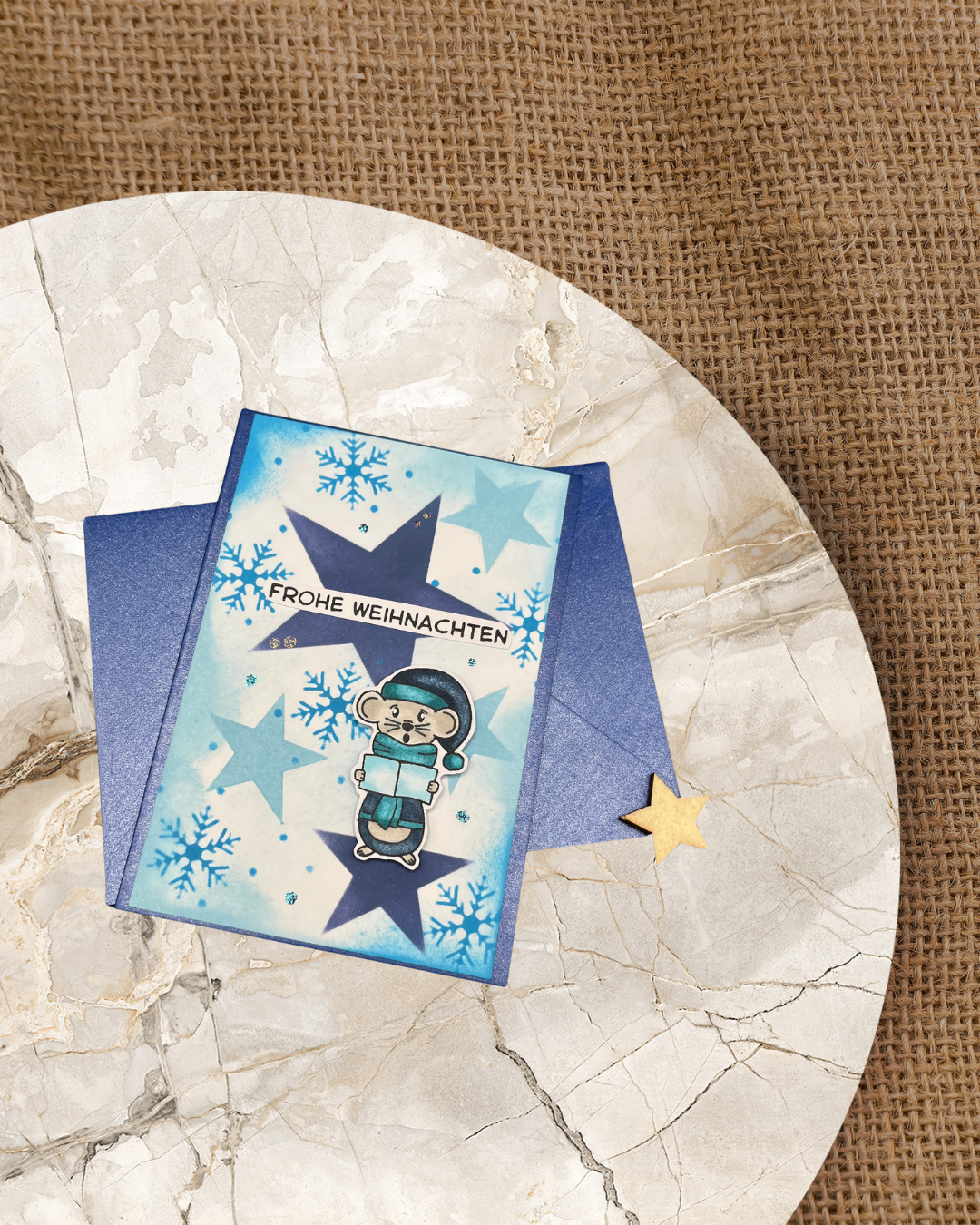 Weihnachtskarte mit singender Maus. Im Hintergrund ein Sterne und Schneeflocken.