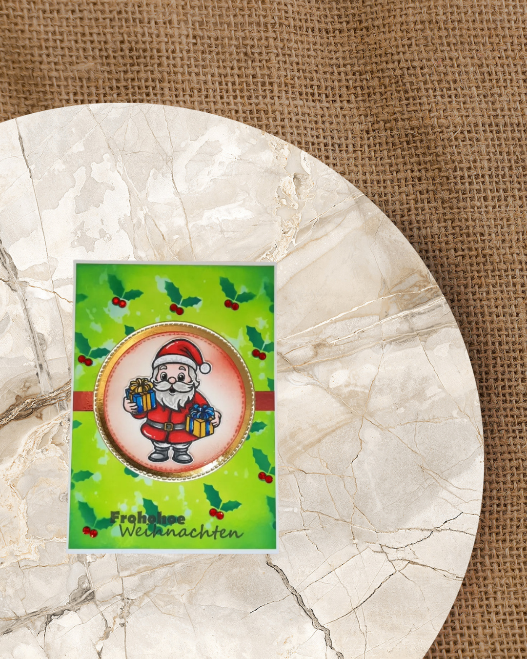 Karte mit einem Weihnachtsmann der Geschenke in der Hand hält. Im Hintergrund viele kleine Ilex mit dem Spruch Frohe Weihnachten