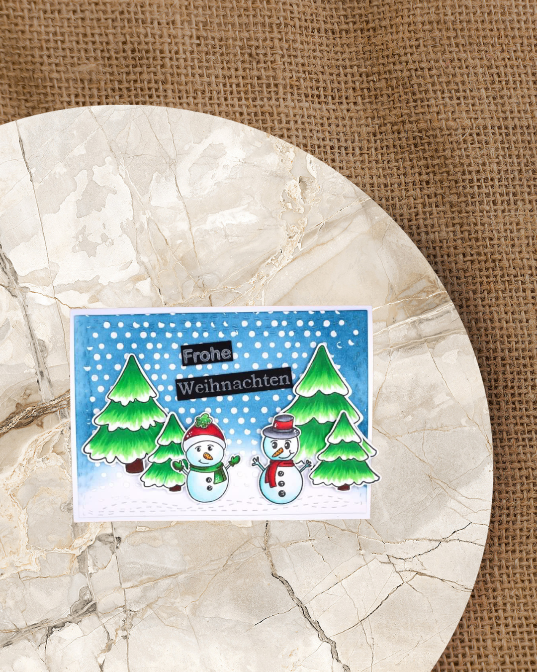 Tannenbäume mit 2 Schneemänner vor 4 Tannen. Blauer Hintergrund mit Schnee