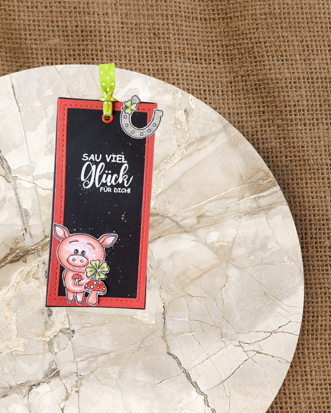 Schwarzes Lesezeichen mit rotem Rand dazu ein Schweinchen mit einen Pilz und Kleeblatt. Spruch Sau viel Glück für dich
