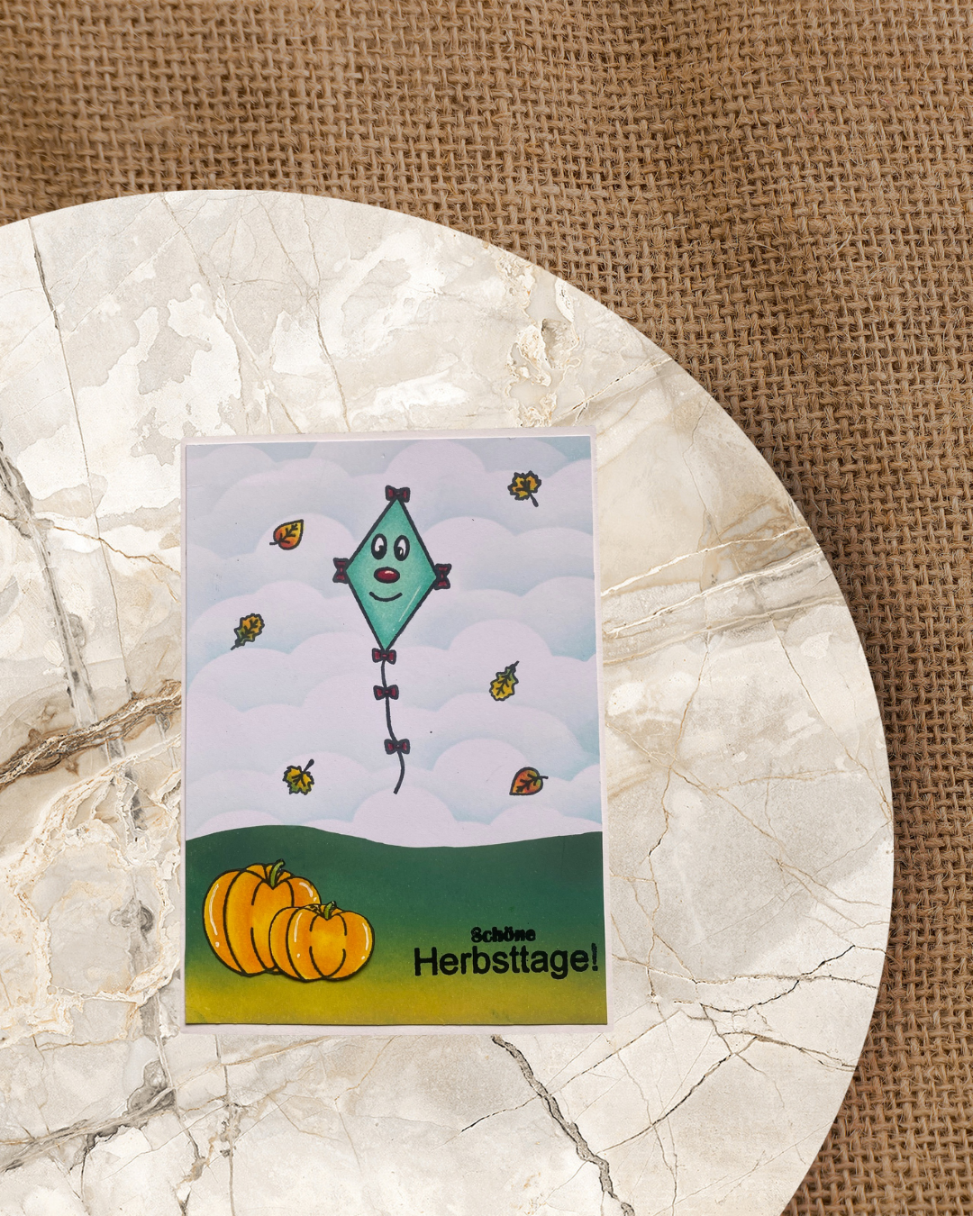 Herbstkarte erstellt mit Stempeln. Drache der fliegt mit bunten Blättern. Kürbisse auf dem Gras und einem Textstempel der Schöne Herbsttage heißt