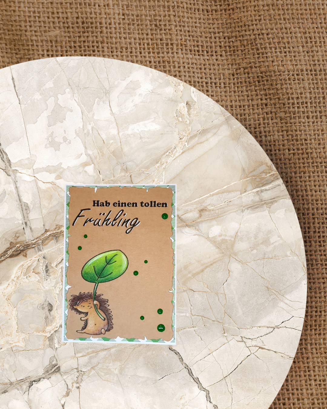 Kraftfarbene Karte mit fliegendem Igel mit einem großen Blatt in der Pfote. Dazu der Spruch Hab einen tollen Frühling