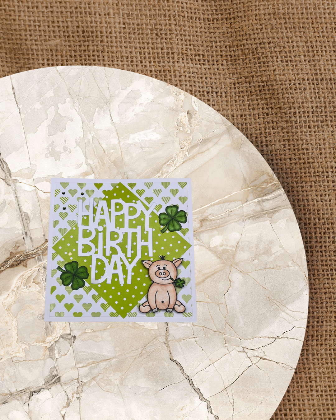 Karte zum Geburtstag mit sitzendem Glücksschweinchen und Kleebklättern