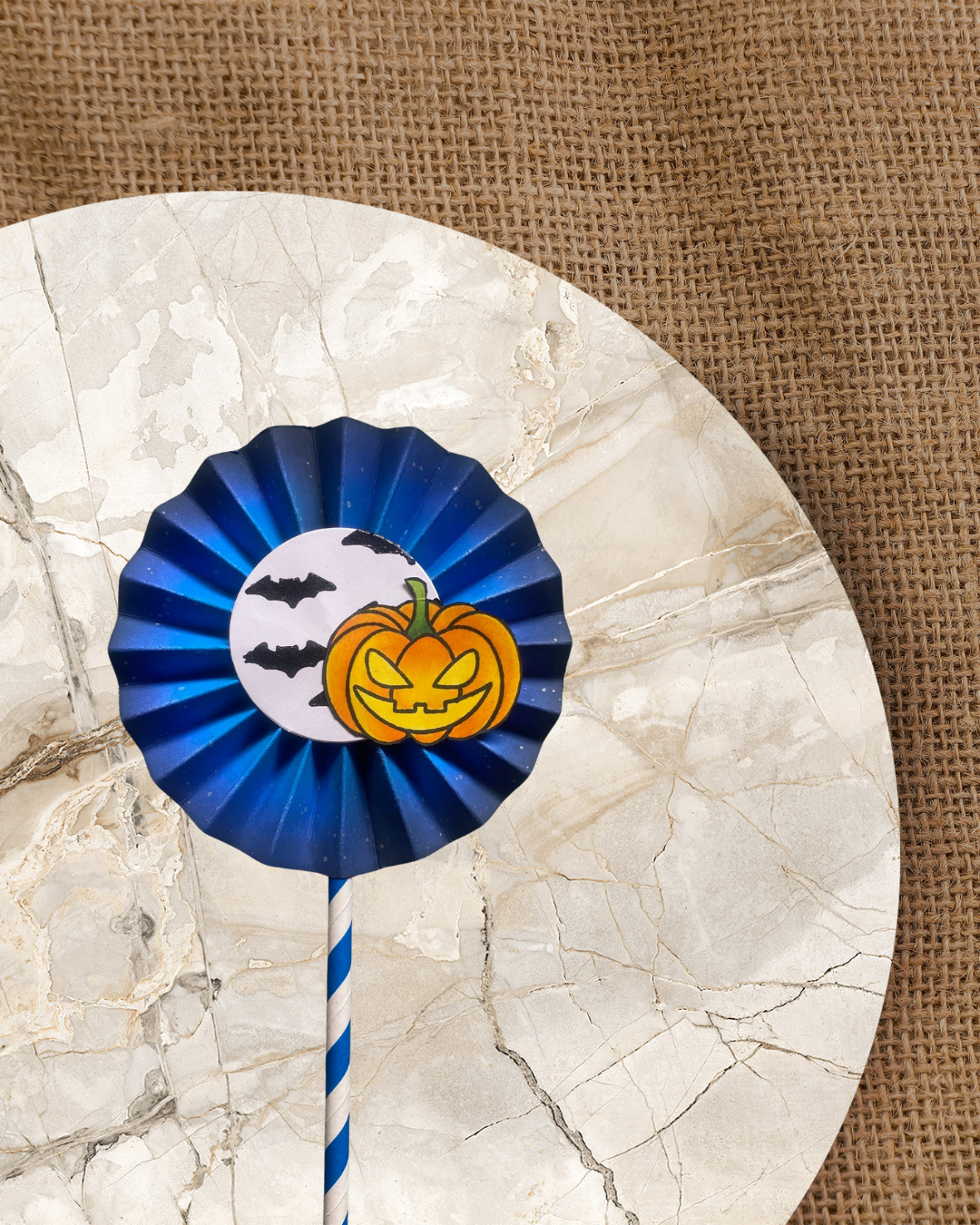 Eine Rosette mit einem Halloween Kürbis mit Stempelabdruck ausgemalt ausgeschnitten und Fledermäusen