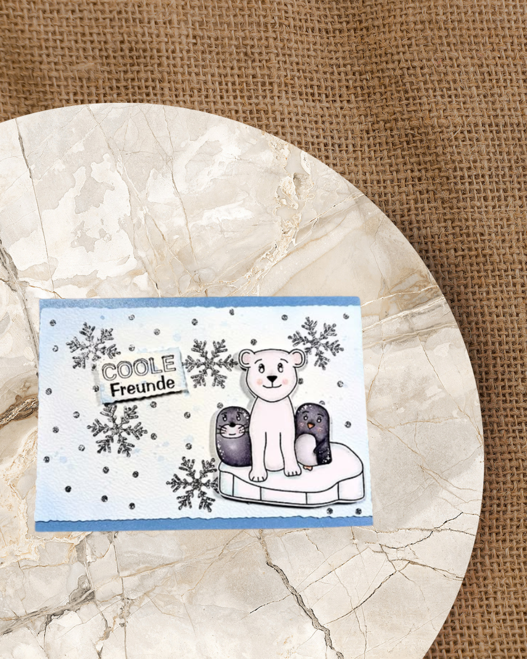 Karte mit blauem Hintergrund, darauf  ein Seelöwe, Eisbär und Pinguin auf einer Eisscholle. Im Hintergrund Schneekristalle und er Spruch Coole Freunde